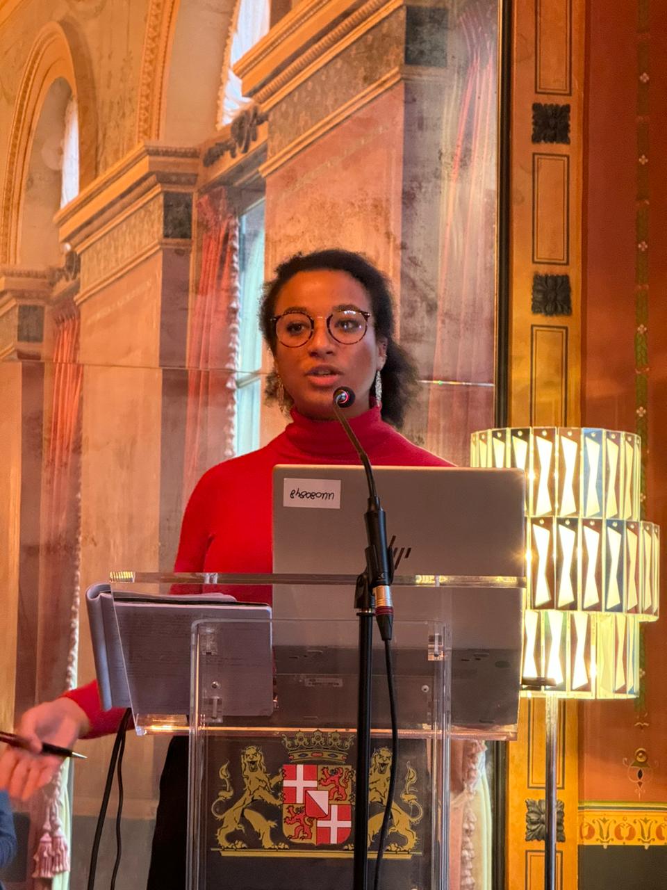 Josephine speaking at a lectern with the coat of arms of Utrecht.