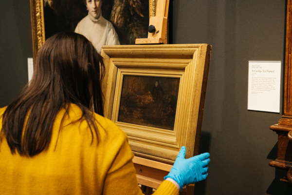 Back of a woman's head who is holding the Beyond Lady Eden painting.